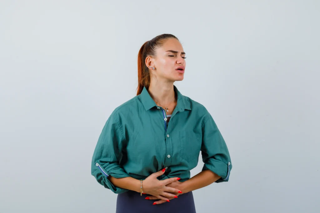 A young woman holding her stomach in pain due to IBS.