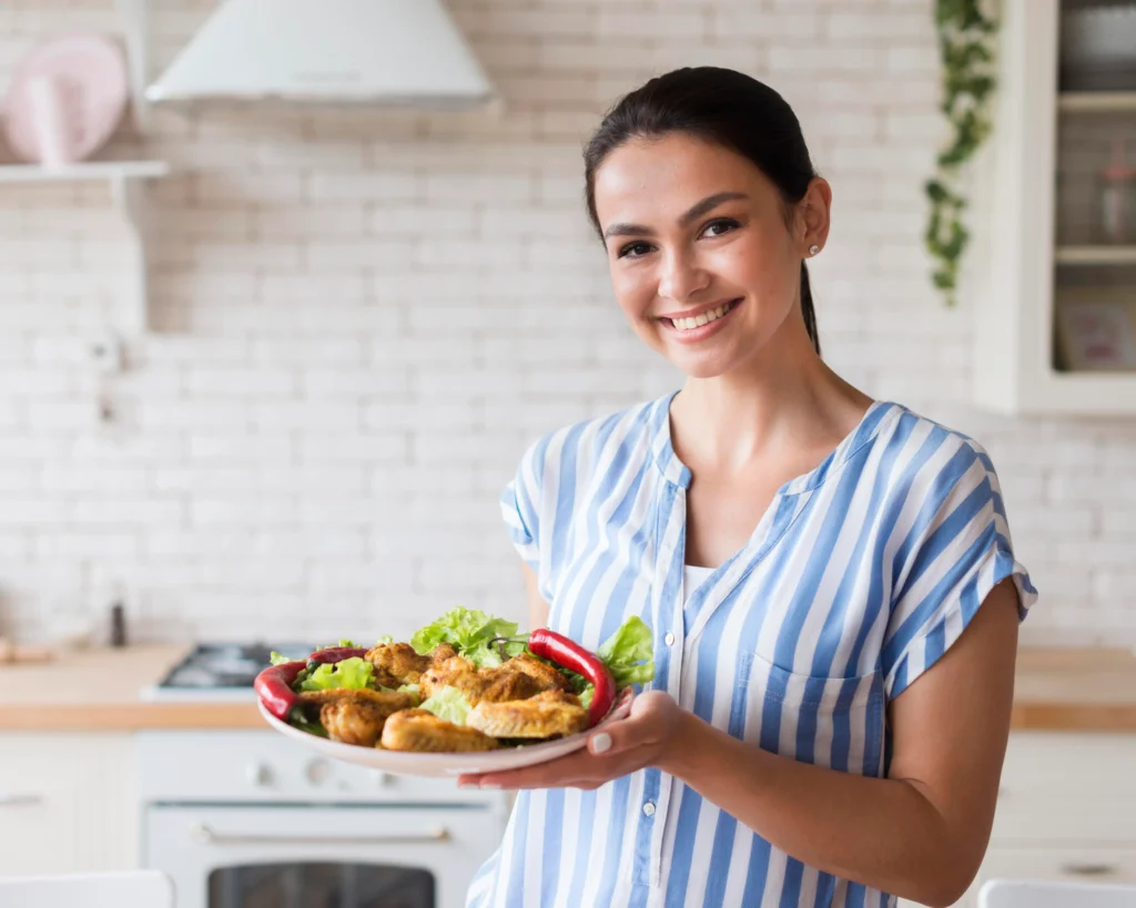A smiling woman holding a plate of healthy food represents the role of personalized nutrition in digestive wellness through MyNutritionRx.