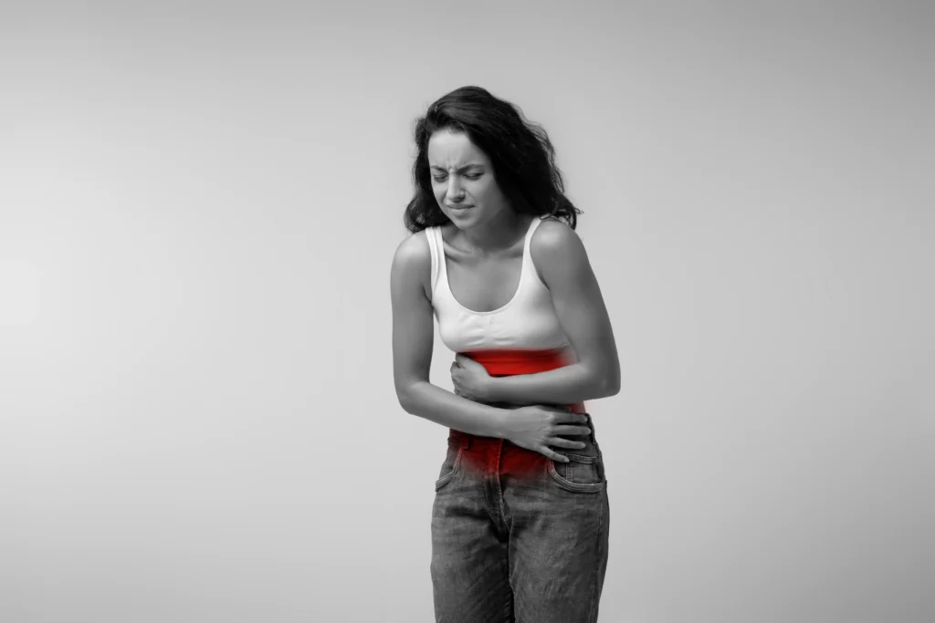 A young woman clutching her stomach in pain, highlighting abdominal discomfort and common digestive disorders in women.