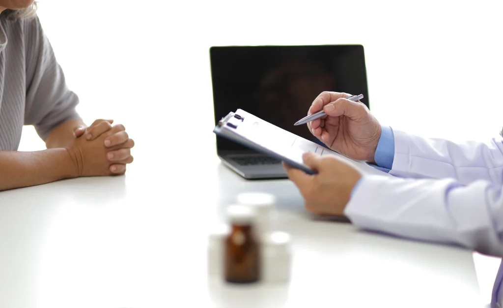 A doctor takes notes during a first appointment with a patient about IBS and IBD symptoms.